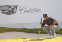 2026 Cadillac Championship: Where to watch, tee times, and schedule Male golfer crouching on a putting green, lining up a putt with a Cadillac banner in the background.