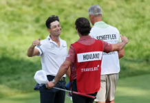 Winners, Losers & Payouts: Viktor Hovland Outlasts Scottie Scheffler in Travelers Championship Thriller Two golfers on a sunny green golf course talk with a caddie wearing a red bib labeled HOVLAND, while a third person with 'SCHEFFLER' on his back watches nearby.