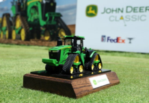 The John Deere Classic Live Leaderboard Small green John Deere tractor model on a wooden base trophy, with John Deere Classic signage in the background.